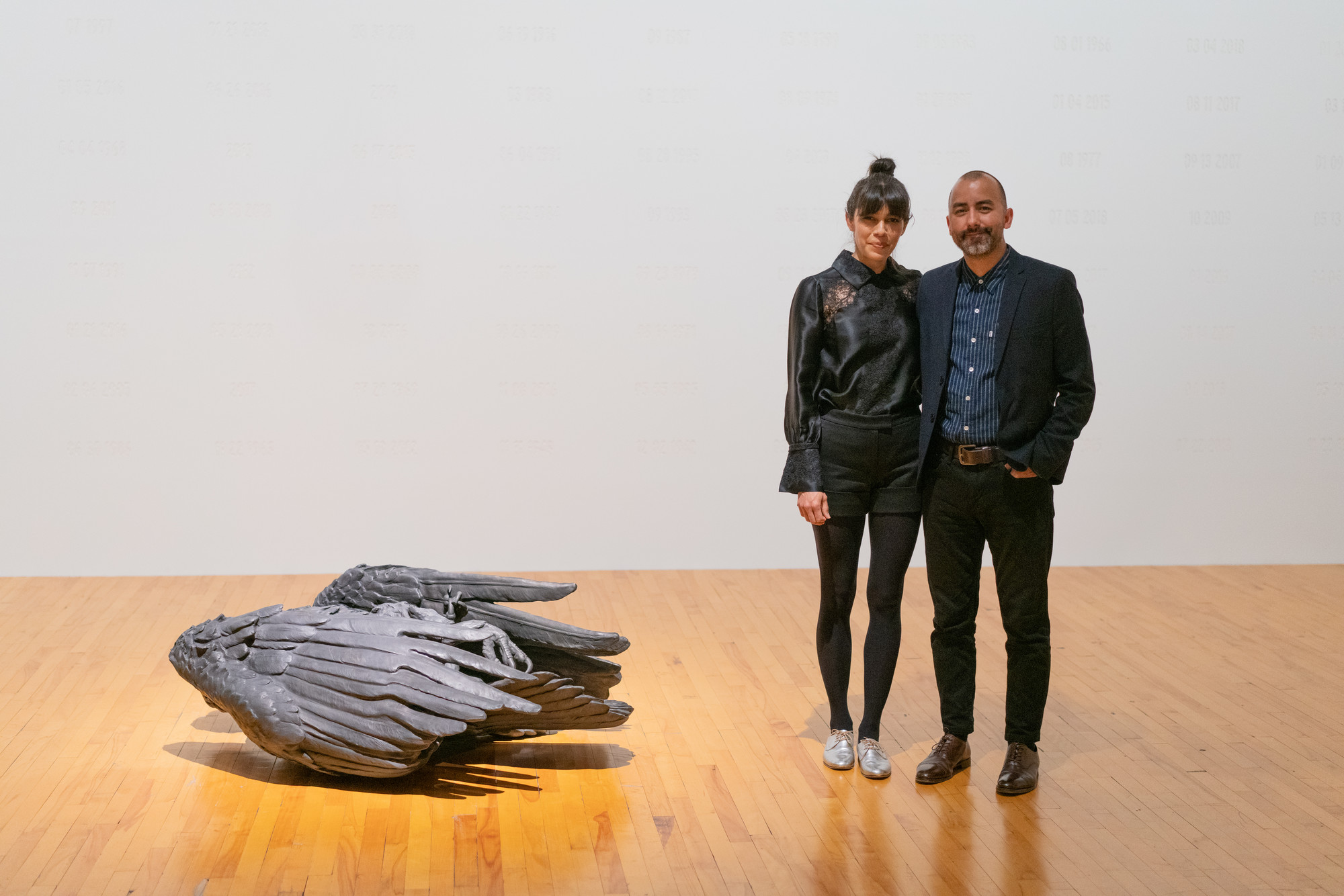 Photograph of Adriana Corral and Vincent Valdez next to their work 'Requiem' in the exhibition 'Suffering From Realness' at MASS MoCA.